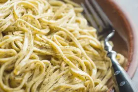 Un primo piatto invitante di tagliolini al limone, conditi con una salsa cremosa e profumata, pronti per essere gustati con una forchetta.