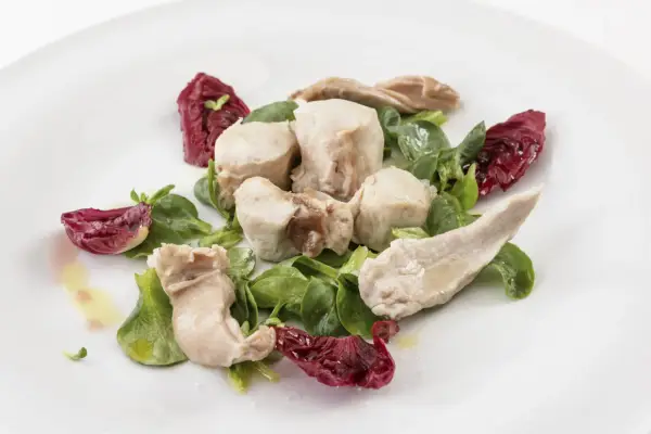 Delicato tonno di coniglio servito con insalata fresca e radicchio croccante, condito con olio d'oliva.