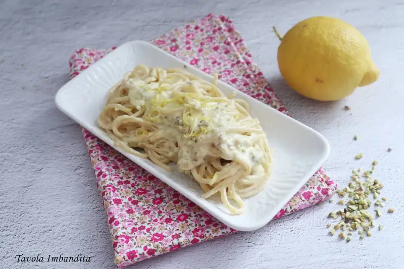 Spaghetti al limone cremosi, un piatto invitante con scorza di limone grattugiata e pistacchi tritati.