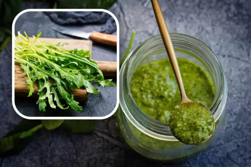 Un mazzetto di rucola fresca su un tagliere e un barattolo pieno di vibrante pesto di rucola, pronto per insaporire i tuoi piatti.